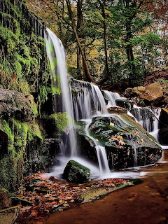 Multi-tiered waterfall flowing over mossy rocks in an autumn forest, New York State