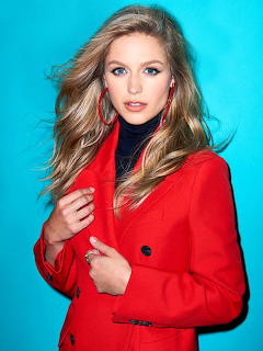 Woman in red blazer with blonde hair against turquoise background