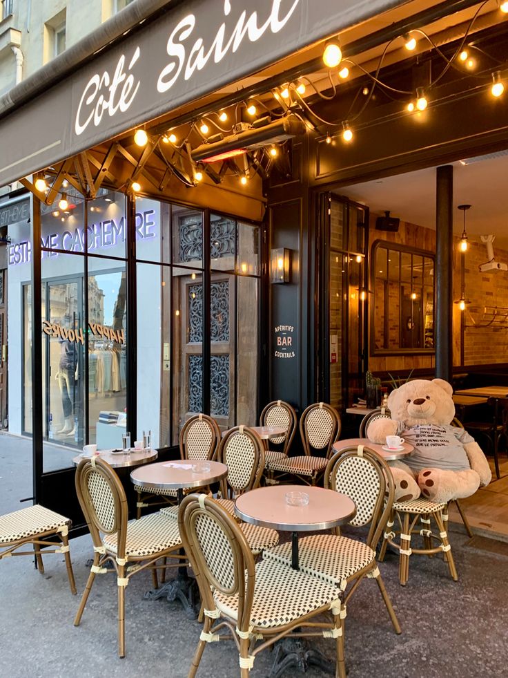 Parisian sidewalk cafe with outdoor seating and flowers along a cobblestone street