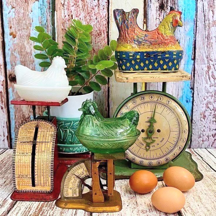 Vintage kitchen decor with chicken figurines, eggs, and an old scale on a rustic table