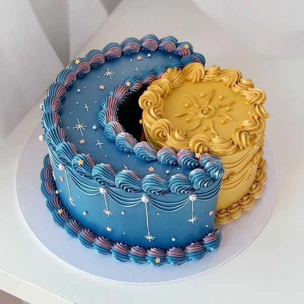 Blue and gold yin-yang cake with piped frosting and star decorations