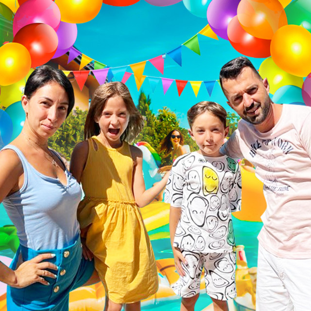 Family posing outdoors under colorful balloons and bunting at a summer party
