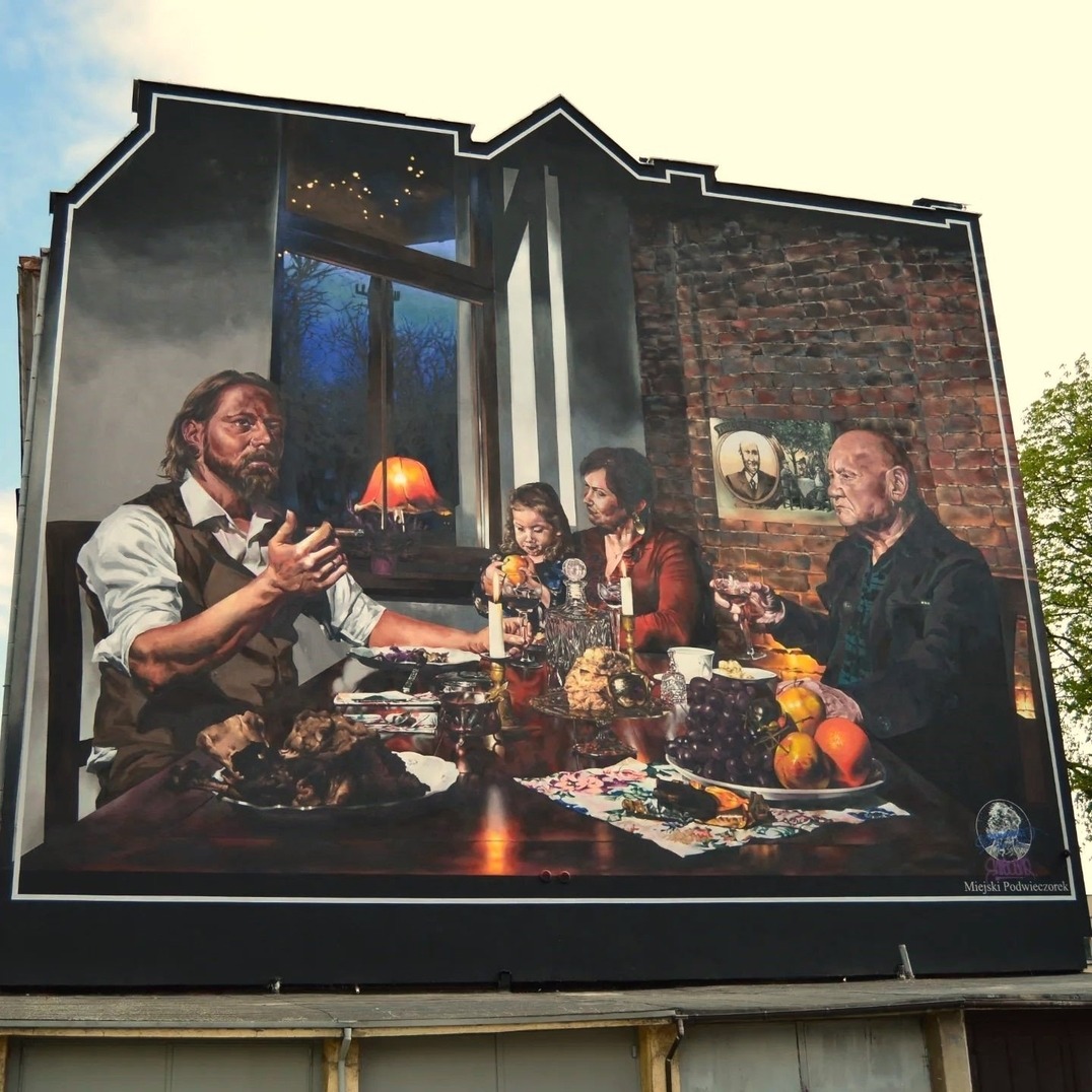 Street art mural of family dining scene on building wall in Racibórz, Poland