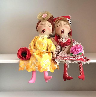 Two handmade fabric dolls in colorful dresses sitting side by side