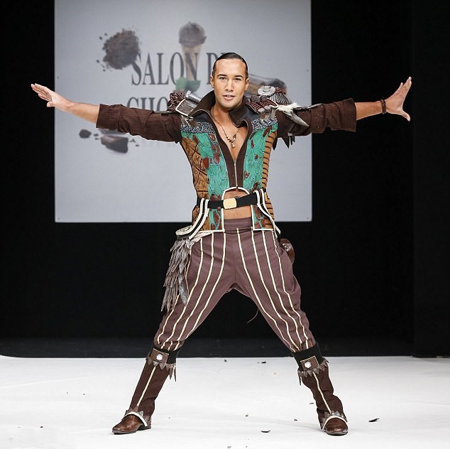 Fashion model posing on a runway in a colorful striped outfit with arms outstretched