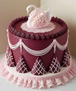 Elegant burgundy cake with white swan and pink flower decoration on top, lattice pattern and draped piping details