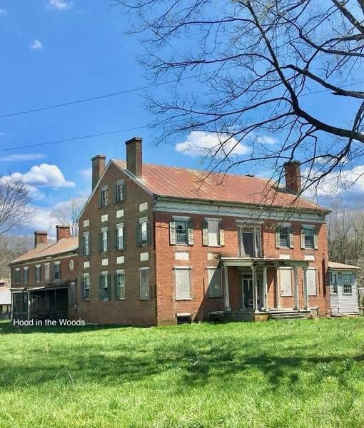 Two-story red brick colonial house with green shutters on lawn with bare trees