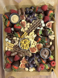 Overhead view of fruit, nut and cheese board with berries, figs, grapes, almonds and honey on wooden surface