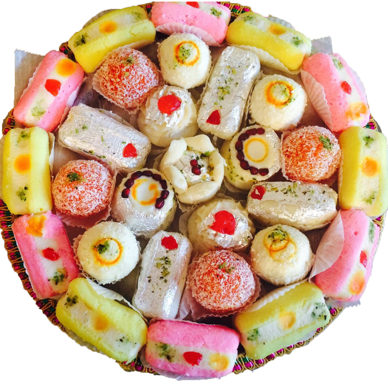 Round platter filled with assorted colorful Indian sweets including barfi, peda, and sandesh