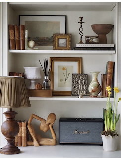 Decorative living room shelves with books, framed pictures, vases, lamp, flowers, and a black speaker