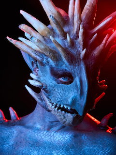Person wearing intricate blue dragon body paint with horns and scales