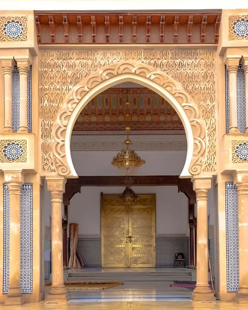 Ornate Moroccan entrance with horseshoe arch, decorative tiles, and golden doors