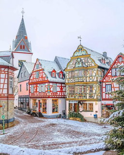 Colorful half-timbered buildings and church steeple in a snowy German town square