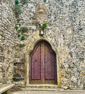 Weathered wooden arched door set in an old stone wall in Erice, Sicily