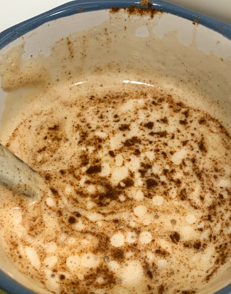 Top view of a foamy cinnamon latte in a mug with a spoon