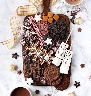 Assorted chocolate desserts and cookies arranged on a wooden serving board with festive decorations