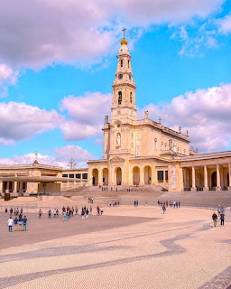 Basilica and bell tower at the Sanctuary of Fatima in Portugal with a wide plaza and visitors