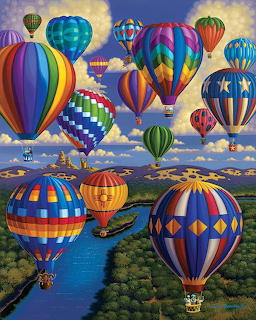 Many colorful hot air balloons with geometric patterns floating over a river and forested landscape