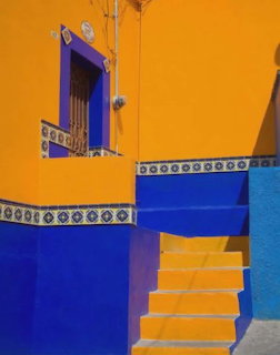 Bright blue and yellow walls with a small staircase and window in a colorful building exterior
