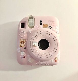 Pastel pink instant camera with cute stickers on a light background