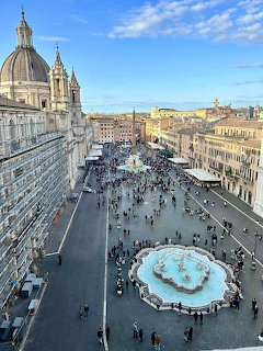 Elevated view of Piazza Navona in Rome with a fountain, church dome, and people in the square