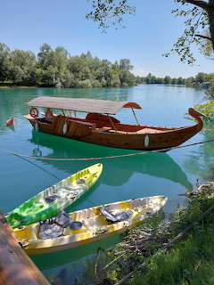 Wooden boats on turquoise river with green trees along shore
