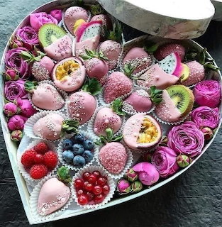 Heart-shaped box with chocolate-covered fruits and pink roses