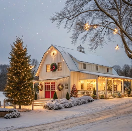 Snowy white farmhouse with lit Christmas tree and holiday decorations at twilight