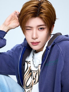 Close-up portrait of a young person with auburn hair in a blue hoodie, winking at the camera.