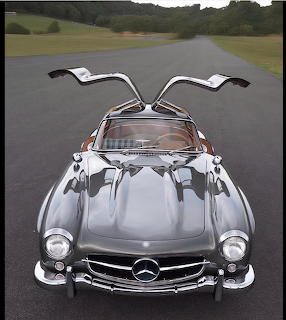 Silver Mercedes-Benz 300SL gullwing doors open viewed from front on road