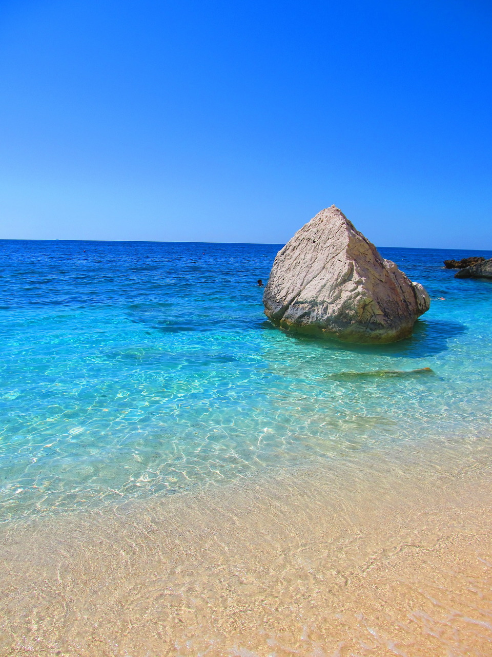 Turquoise Mediterranean sea with large rock on sandy beach, Cala Mariolu, Sardinia
