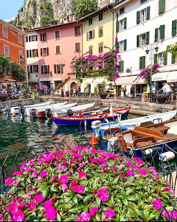 Boats in a harbor with pastel buildings and pink flowers in Limone sul Garda, Italy