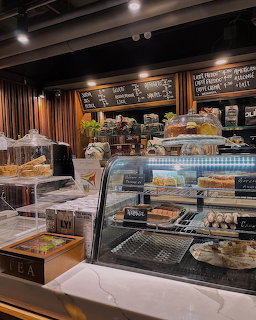 Cafe interior with glass pastry display case, baked goods, and chalkboard menu on the wall