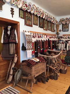Interior of a folk museum with embroidered garments, woven textiles, and antique wooden tools
