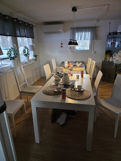 White dining table with chairs and place settings in a bright Scandinavian dining room with wood floors