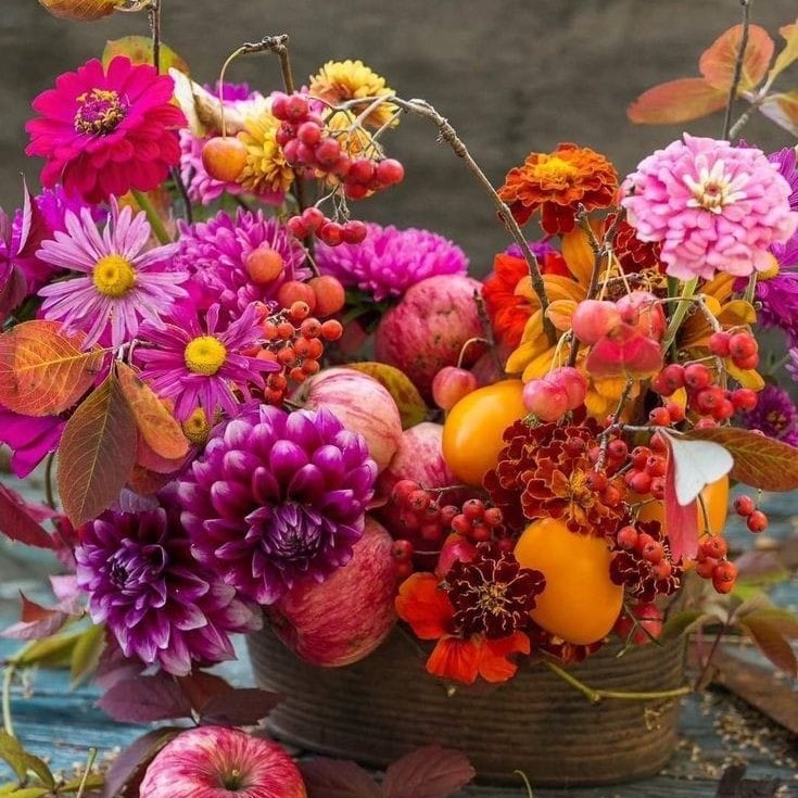 Colorful autumn flower arrangement in a basket with pumpkins, apples, and berries