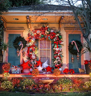 House porch decorated with Christmas wreaths, garlands, lights, and festive ornaments at dusk