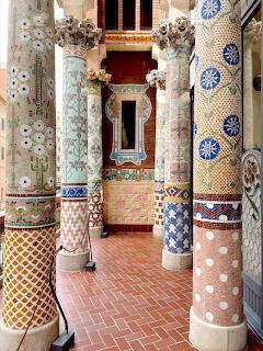 Ornate mosaic columns in a decorated corridor with arches and brick floor