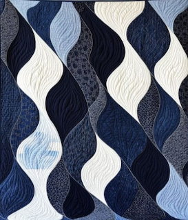 Quilt featuring curved wave shapes in blue, gray and white fabric columns