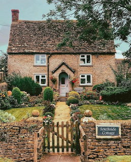 Stone cottage with wooden gate entrance and garden path leading to arched doorway