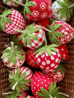 Collection of handmade fabric strawberries with green felt tops arranged in a wicker basket