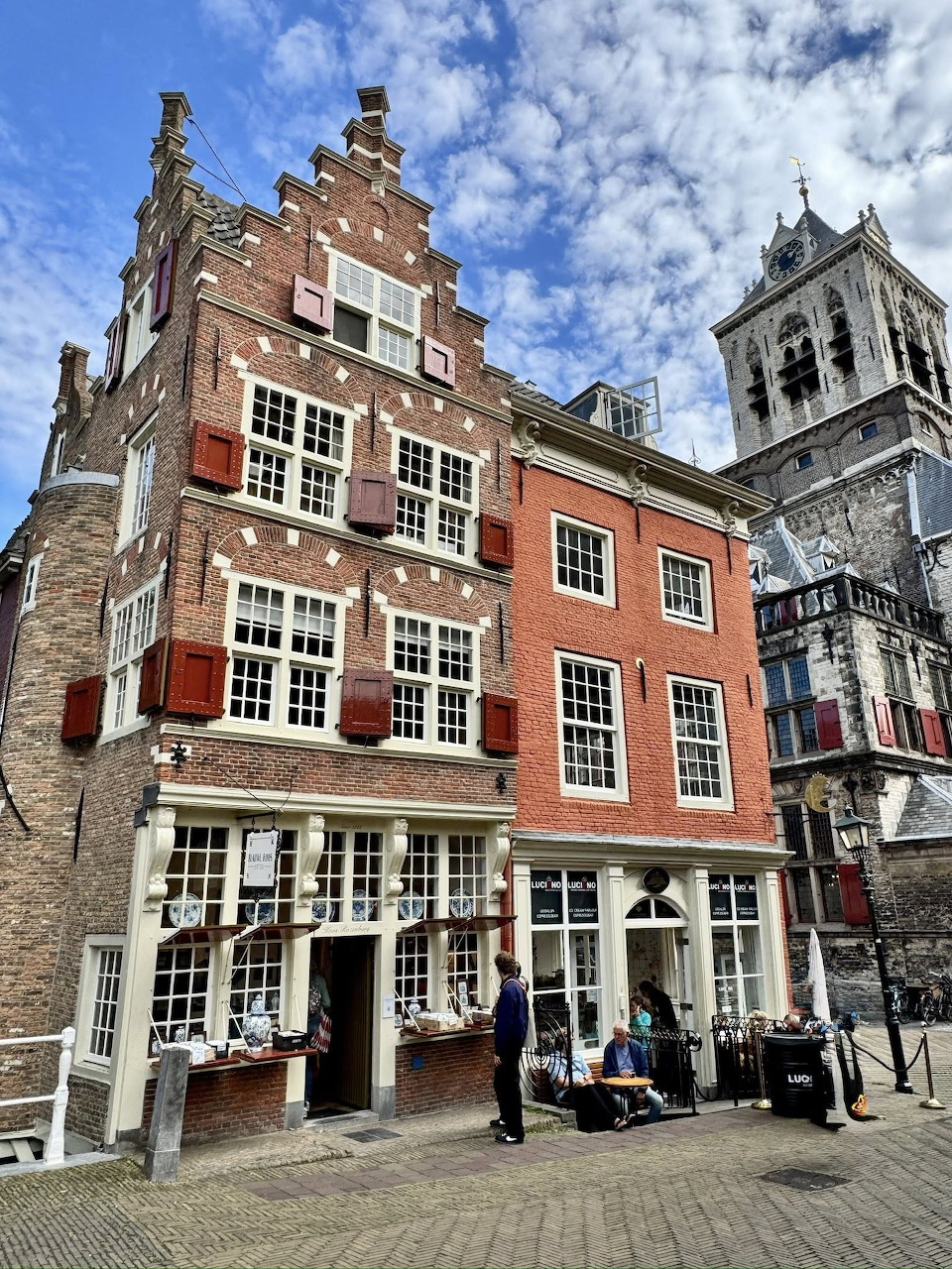 Historic brick houses and a church tower on a cobblestone street in Delft