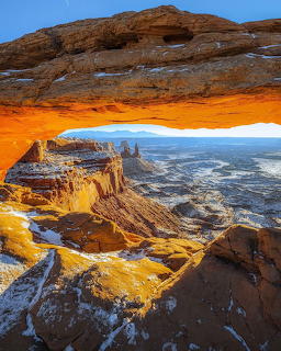 Sunlit rock arch overlooking a canyon landscape in Canyonlands, Utah
