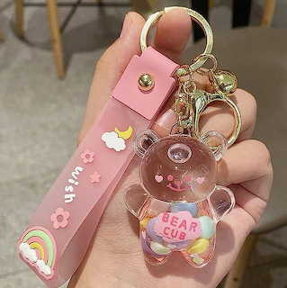 Hand holding pink keychain with transparent bear charm containing rainbow beads and pink strap
