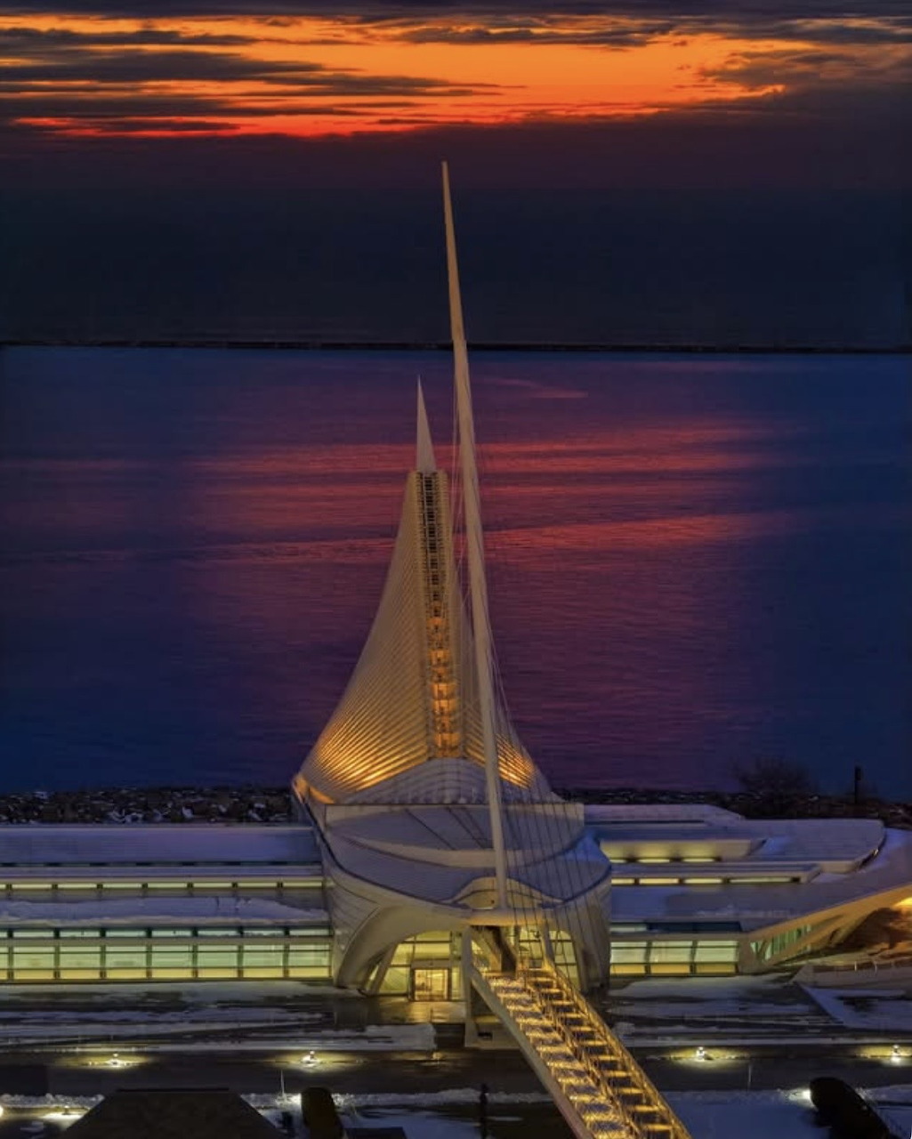Milwaukee Art Museum with illuminated white sails at sunset over Lake Michigan