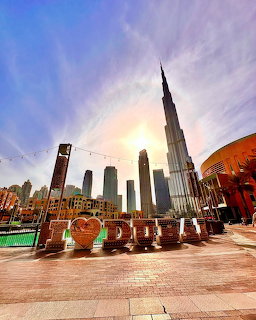 Burj Khalifa skyscraper in downtown Dubai with a plaza and large Dubai sign in front