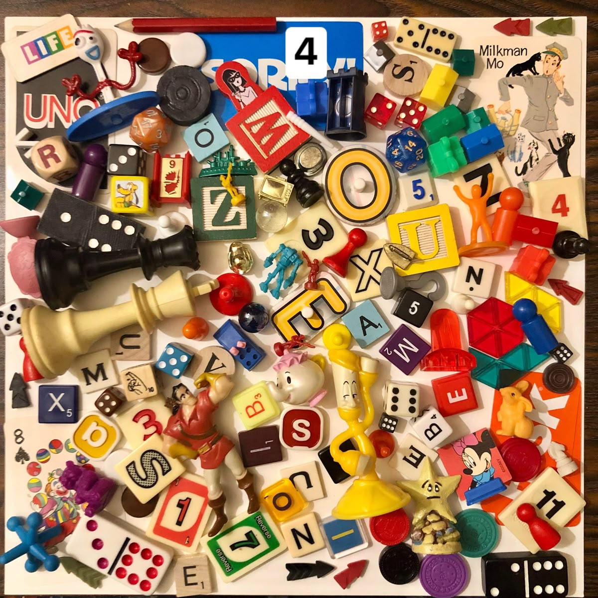Overhead view of jumbled toy letters, dice, game pieces and small objects in various colors