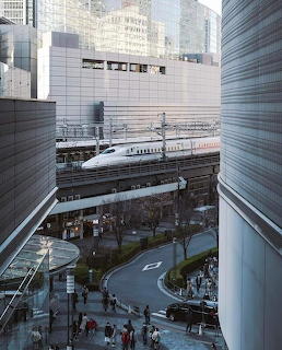 White bullet train traveling between modern city buildings in Japan