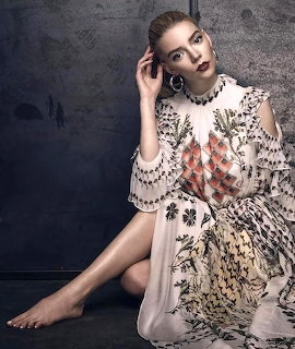 Woman in white floral dress seated against dark textured wall
