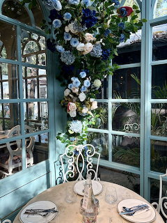 Round table for two by turquoise windows with a tall blue and white floral arrangement